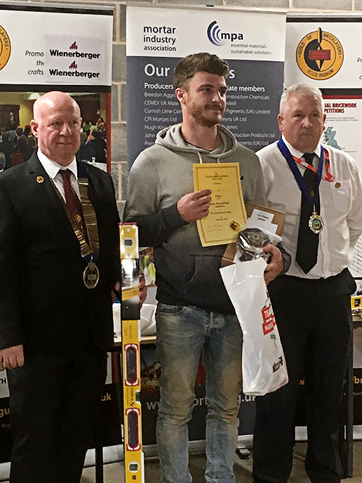 Junior winner 2019 - Junior section winner, Tom Taylor, Wiltshire College, receives his awards from president of the Guild of Bricklayers, Kevin Harold (left) and chair of the guild�s north west section, Jeff Dunn

