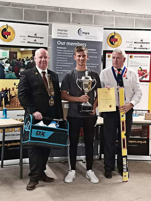 Senior winner 2019 - President of the Guild of Bricklayers, Kevin Harold (left) and chair of the guild�s north west section, Jeff Dunn, present senior winner, Adam Batty of Barnsley College with his awards